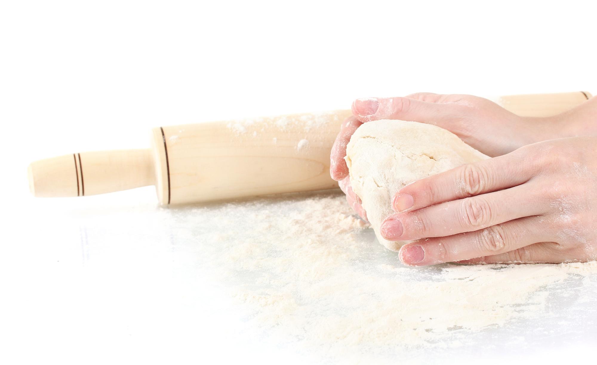 Student rolling pasta on a floured board